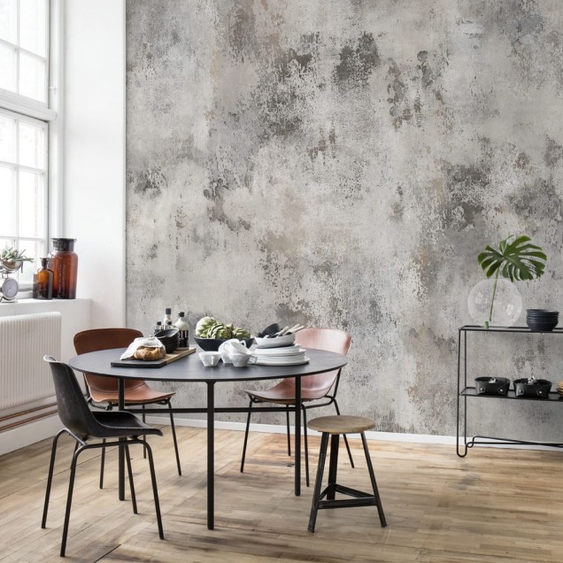Tapet 3D Patina, cu aspect de beton, într-un dormitor cu pat dublu, cu lenjerie de pat albastră, perne decorative și o canapea cu o pătură de blană