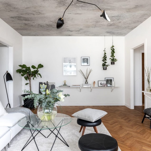 Tapet 3D Patina, cu aspect de beton, într-un dormitor cu pat dublu, cu lenjerie de pat albastră, perne decorative și o canapea cu o pătură de blană