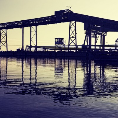 Imagine cu un tapet cu un peisaj al unui port, cu un macaz în siluetă, apus de soare și reflexii ale apei.