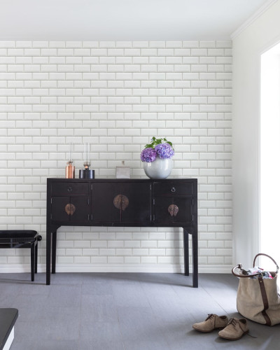 Wallpaper cu aspect de faianta alba, Bistro Tiles, White, arata un hol cu o canapea neagra si o geanta de piele maro in fata
