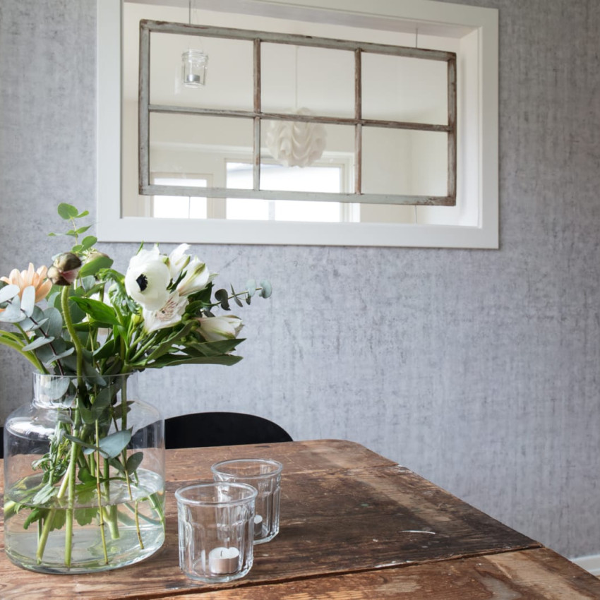 Tapet Solid Blush - O nuanță delicată de roz, perfectă pentru living, dormitor sau baie. Imaginea prezintă o cameră cu canapea, covor, plante și alte decorațiuni, toate armonizate cu culoarea tapetului.