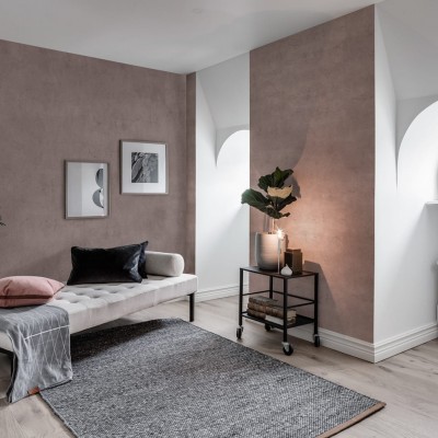 Tapet Solid Blush - O nuanță delicată de roz, perfectă pentru living, dormitor sau baie. Imaginea prezintă o cameră cu canapea, covor, plante și alte decorațiuni, toate armonizate cu culoarea tapetului.