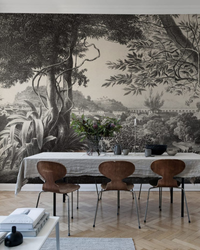Tapet de perete Mirage cu design grafic, care prezintă o vedere a unei păduri tropicale cu o panoramă a unei clădiri în depărtare.