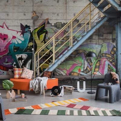 Tapet foto cu design urban - Stairway Graffiti, care prezintă un perete cu grafitti colorat, o scară metalică și beton brut.