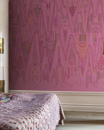 Imagine cu wallpaper-ul Manhattan, Hot Pink, un design abstract al orașului, cu un ton de roz aprins cu accente galbene și portocalii, instalat pe peretele unui dormitor.