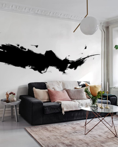 Tapet abstract negru pe fond alb, cu un design minimalist. Tapetul este aplicat pe un perete din sufragerie, deasupra unei canapele gri, cu o masă de cafea din sticlă și un scaun verde.