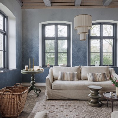 Tapet Ash Gradient, Blue cu aspect de beton, decorat cu o canapea, o masuta si flori roz