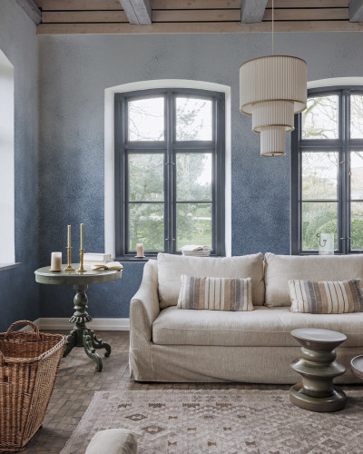 Tapet Ash Gradient, Blue cu aspect de beton, decorat cu o canapea, o masuta si flori roz