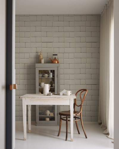 Tapet cu aspect de cărămidă gri, Flight of Tiles, Clay, într-o încăpere cu o masă, un scaun și un dulap cu uși de sticlă.