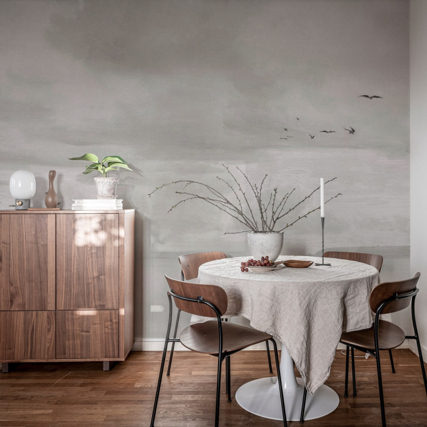 Seabirds Black & White wallpaper by Rebel Walls, featuring a hand-drawn landscape with birds flying, a cloudy sky and a coastline. The wallpaper is perfect for adding a touch of sophistication to any room.