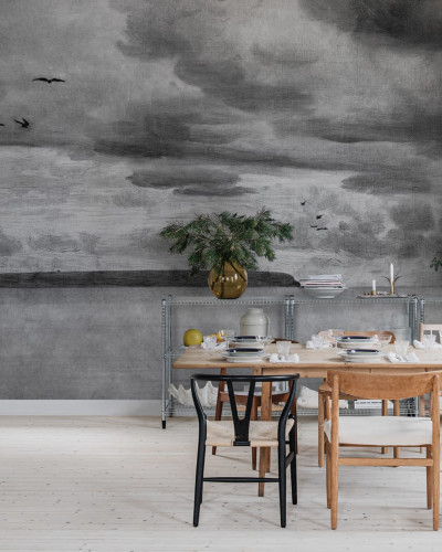 Seabirds Black & White wallpaper by Rebel Walls, featuring a hand-drawn landscape with birds flying, a cloudy sky and a coastline. The wallpaper is perfect for adding a touch of sophistication to any room.