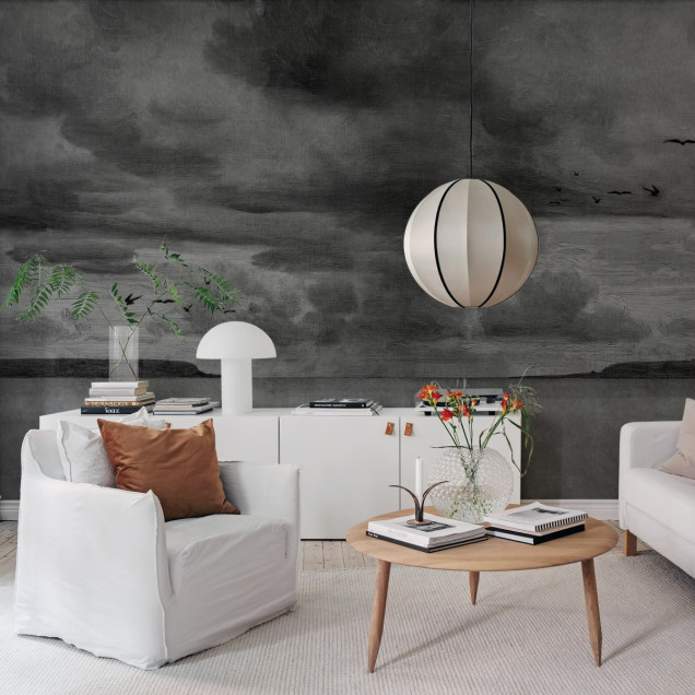 Seabirds Black & White wallpaper by Rebel Walls, featuring a hand-drawn landscape with birds flying, a cloudy sky and a coastline. The wallpaper is perfect for adding a touch of sophistication to any room.