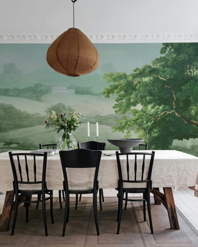 Tapet Vintage Tree, Green, cu un design elegant cu un copac impunator si un peisaj verde, decorand un living cu o masa si scaune.