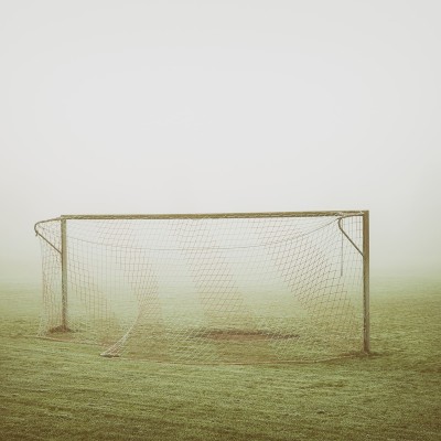 Tapet cu imagine cu o poartă de fotbal în ceață, pe un câmp verde.