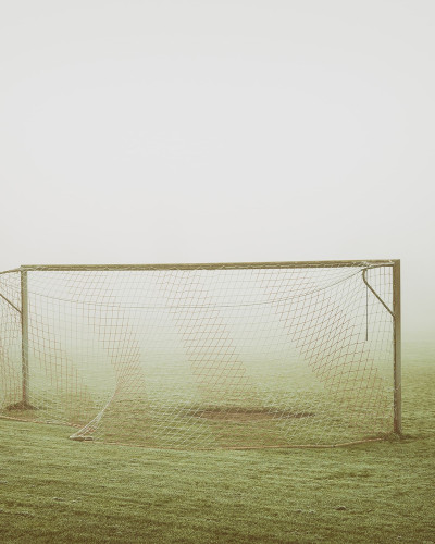 Tapet cu imagine cu o poartă de fotbal în ceață, pe un câmp verde.