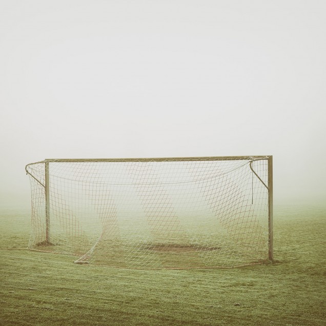 Tapet cu imagine cu o poartă de fotbal în ceață, pe un câmp verde.