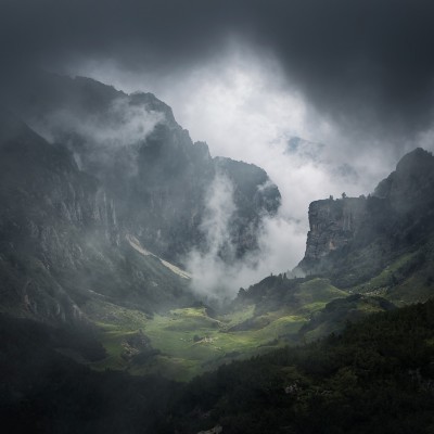 Tapet cu design Foggy Valley, ce prezintă o vale înconjurată de munți înalți acoperiți cu ceață.
