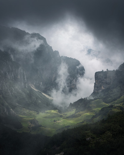Tapet cu design Foggy Valley, ce prezintă o vale înconjurată de munți înalți acoperiți cu ceață.