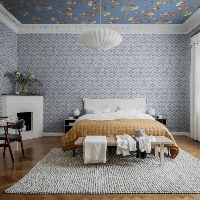 Tapet cu model de valuri albastre, decorat într-un dormitor cu pat și covor gri