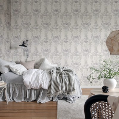 Tapet Claws & Clams, Sand, cu un imprimeu nautic elegant, cu scoici, crabi și alge marine, pe un fundal gri deschis. Tapetul este prezentat într-un interior modern, cu un pat, o canapea și o masă de cafea.