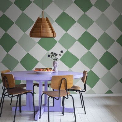 Tapet Tremble Green, model geometric cu pătrate, nuanțe de verde și alb, aplicat pe un perete din sufragerie, lângă o masă cu scaune.