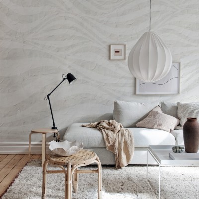 Tapet cu design modern, Graphic Hills, gri deschis,  cu un design inspirat din formele naturale. Tapetul se afla intr-un living amenajat modern, langa un canapea alba, o masuta din lemn si o lampa de birou.