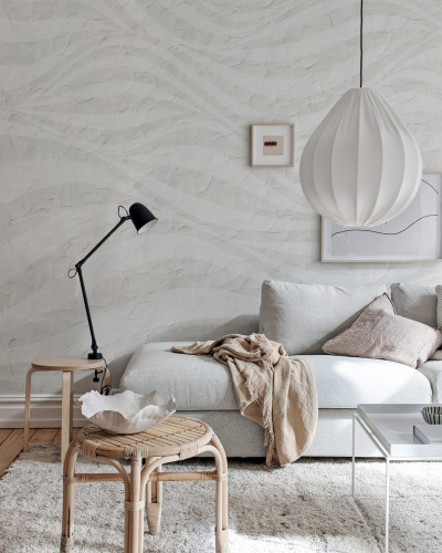 Tapet cu design modern, Graphic Hills, gri deschis,  cu un design inspirat din formele naturale. Tapetul se afla intr-un living amenajat modern, langa un canapea alba, o masuta din lemn si o lampa de birou.