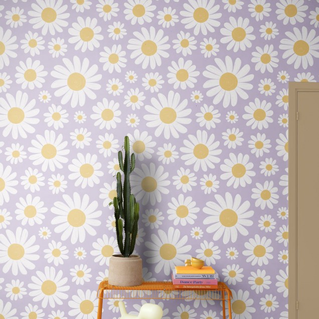 Tapet floral cu margarete albe pe fond liliac, decorand un living cu canapea maro si o masa cu flori.