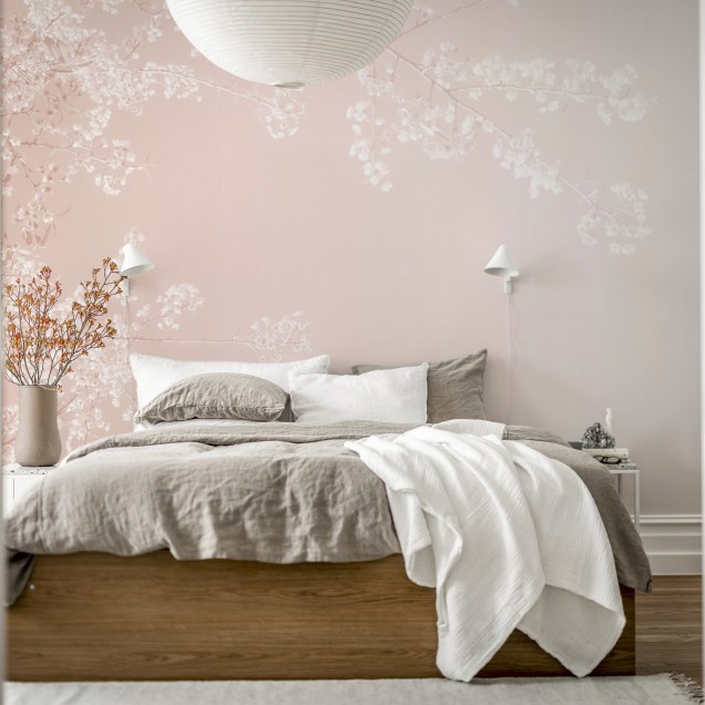 Tapet floral roz cu ramurele delicate pe un fond pastelat. Se vede o canapea alba cu perne si o lampa pe un birou.