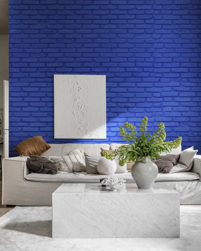 Wallpaper cu aspect de cărămidă, în nuanța cobalt, în decorul unei camere cu canapea albă și o masă de cafea din marmură.