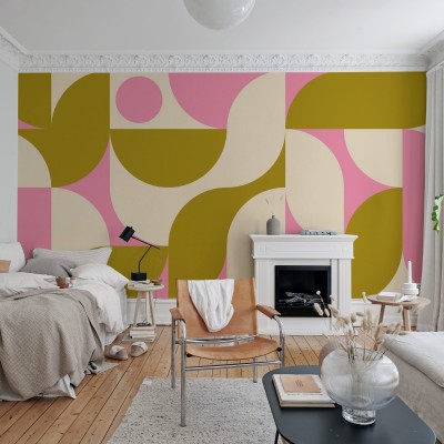 Tapet geometric modern, cu design vibrant, in tonuri pastelate de roz, galben si crem. Tapetul este aplicat pe un perete din camera de zi, decorata cu mobilier modern.