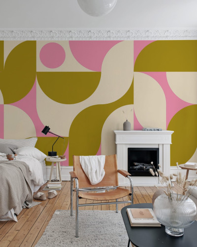 Tapet geometric modern, cu design vibrant, in tonuri pastelate de roz, galben si crem. Tapetul este aplicat pe un perete din camera de zi, decorata cu mobilier modern.
