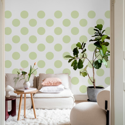 Tapet cu puncte mari, de un verde deschis, decorând un living modern cu canapea și o plantă.