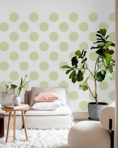 Tapet cu puncte mari, de un verde deschis, decorând un living modern cu canapea și o plantă.