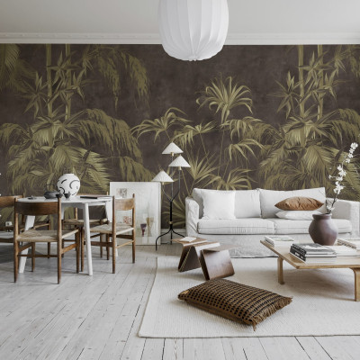 Un tapet cu un design exotic, Golden Jungle, Dark, care prezintă frunze aurii pe un fundal brun-cenusiu. Tapetul este amplasat pe un perete din living, alături de o canapea albă, o masă de cafea și o bibliotecă.