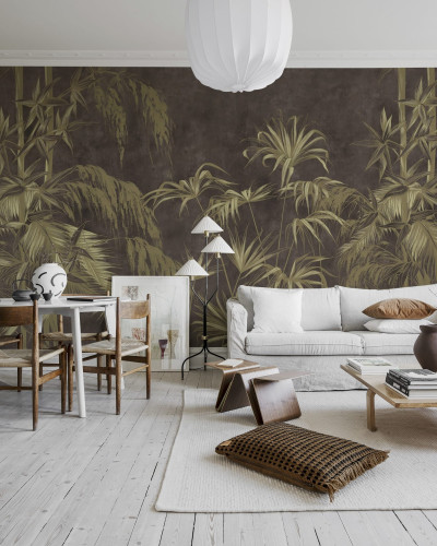 Un tapet cu un design exotic, Golden Jungle, Dark, care prezintă frunze aurii pe un fundal brun-cenusiu. Tapetul este amplasat pe un perete din living, alături de o canapea albă, o masă de cafea și o bibliotecă.