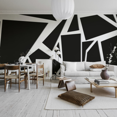Tapet geometric abstract în culori negru și alb, aplicat pe un perete din living, lângă o canapea albă, cu un covor alb și un fotoliu maro.