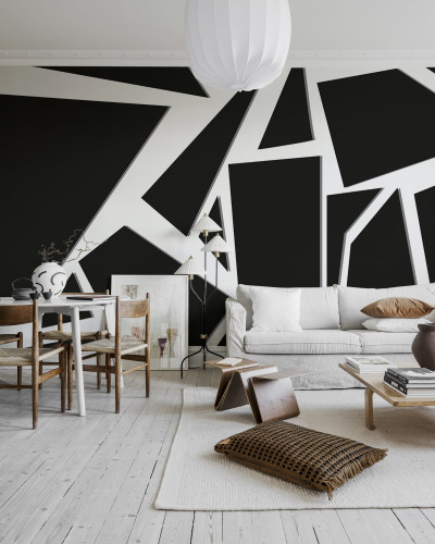Tapet geometric abstract în culori negru și alb, aplicat pe un perete din living, lângă o canapea albă, cu un covor alb și un fotoliu maro.