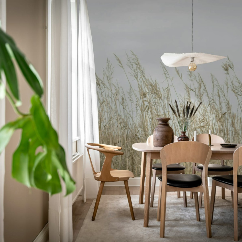Tapet Reed Meadow, Gray, cu iarbă înaltă în tonuri de gri, într-un living cu o masă de dining și scaune negre.