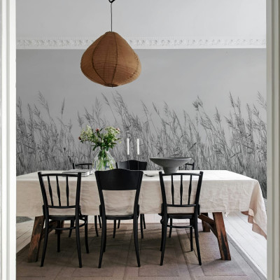 Tapet Reed Meadow, Gray, cu iarbă înaltă în tonuri de gri, într-un living cu o masă de dining și scaune negre.
