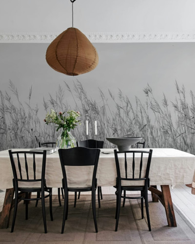 Tapet Reed Meadow, Gray, cu iarbă înaltă în tonuri de gri, într-un living cu o masă de dining și scaune negre.