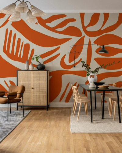 Tapet abstract cu frunze in nuante de terracotta, aplicat pe un perete in living,  arată o masă de dining, scaune, un dulap și o canapea