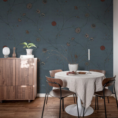 Wallpaper floral in nuante de albastru, cu flori delicate si ramuri subtiri, incadrand o masa cu scaune intr-o camera luminoasa.