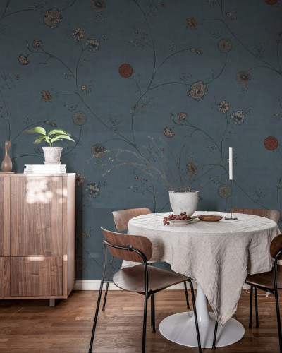 Wallpaper floral in nuante de albastru, cu flori delicate si ramuri subtiri, incadrand o masa cu scaune intr-o camera luminoasa.