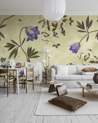 Tapet floral cu flori delicate, de un lila vibrant, pe un fundal verde deschis. Tapetul este aplicat pe un perete din living, lângă o canapea albă și o masă de cafea.