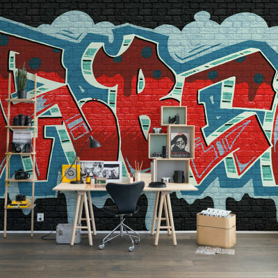 Tapet Rebel Graffiti, Red, cu un design urban in rosu, albastru si verde. Tapetul este pozitionat pe un perete din camera de zi, alaturi de o masa de lucru.