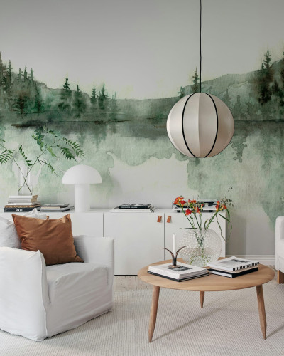 Imagine cu tapet watercolor cu design de pădure verde. Tapetul este lipit pe peretele unei camere amenajate în stil modern, cu canapea albă, fotolii albe și o masă de cafea din lemn.