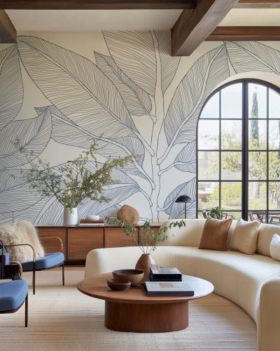 Tapet cu design de frunze mari, albastre, conturate, pe un fundal crem, într-un living modern.