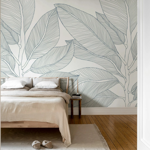 Tapet cu design de frunze mari, albastre, conturate, pe un fundal crem, într-un living modern.