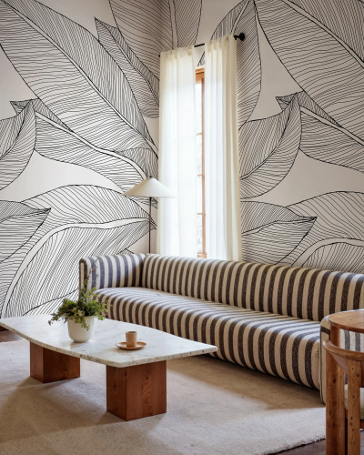 Fototapet cu design de frunze stilizate în linii negre pe un fundal alb, într-un living modern.